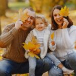 family smiling and playing in autumn leaves after visiting our dentist in Brookhaven, PA